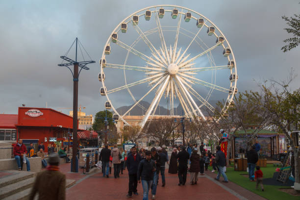 Tourists enjoying the Victoria and Alfred waterfont and the Ferris Wheel, Cape Town, South Africa.