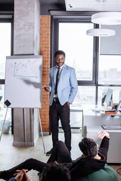 istock Young black man presenting an office meeting at a flip chart. 2161406180