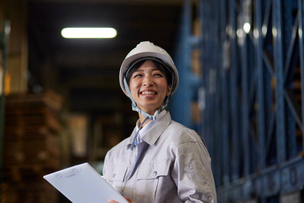 A woman wearing work clothes inspecting a factory
