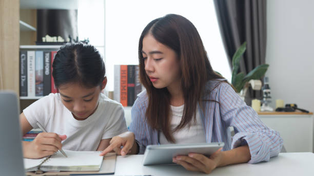 istock Asian siblings doing homework on a table at home 2161411860