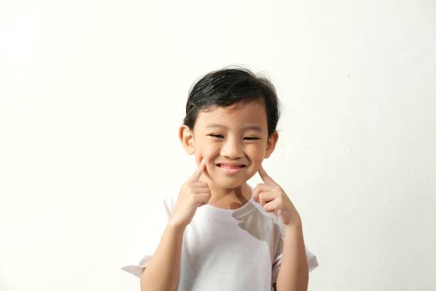 istock A smiling child points to their cheeks, radiating joy and playfulness. 2161412083