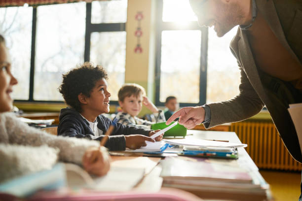 istock Happy black schoolboy talking to his teacher on a class at elementary school. 2161421762
