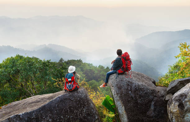 istock Two people are sitting on a rock in the mountains 2161426492