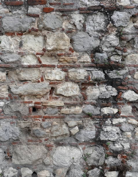 Art Brick Wall with Shabby White Plaster. Painted Whitewashed Stone Wall Vintage Background. Grungy Wall for Design Vertical Banner