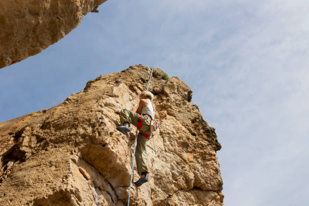 istock A woman is climbing a rock wall with a rope 2161436686