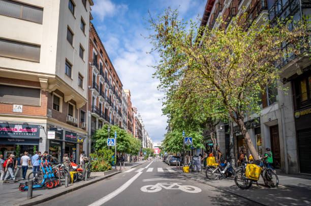 Madrid, Spain. 29 June 2024. Tree lined Mayor Street in Madrid with people at a shop.