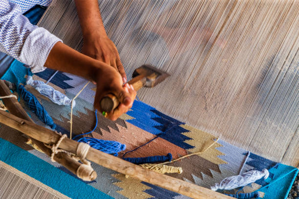 Indian man weaving durries. The durry (Rug) is weaved out of cotton or wool. The geometric designs are produced by tapestry technique which is a slow process using separate bobbins or butterflies for each colour across the width interlocking with the adjacent coloured yarn.  This old fashined form of weaving is very popular in Rajasthan, specially in Salawas village near Jodhpur.