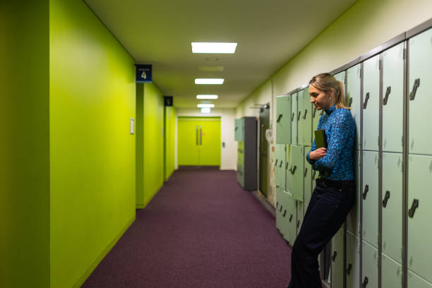Depressed teen student standing by locker