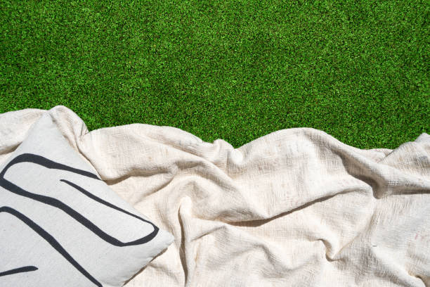 istock White blanket and decorative pillow on green grass 2161446379