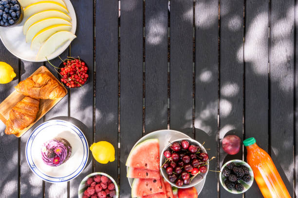 Wooden picnic table with berries, pastries, cake and refreshing drink