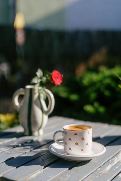 ceramic coffee cup and a white vase of rose flowers