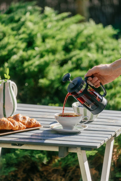 istock Hand pouring tea in white teacup on picnic table in garden 2161446449