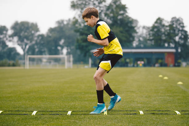 istock Youth soccer player skipping on training ladder. Young boy running fast and exercising using training equipment. Football player improving speed on training pitch 2161447913