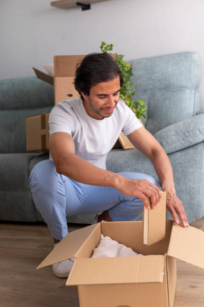 istock Man unpacking boxes in his new home, settling in the living room 2161448708
