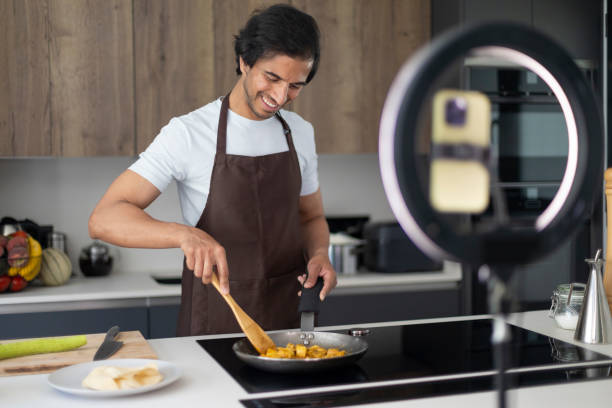 istock Chef in apron preparing a meal in a contemporary kitchen, with camera setup for recording. 2161448744