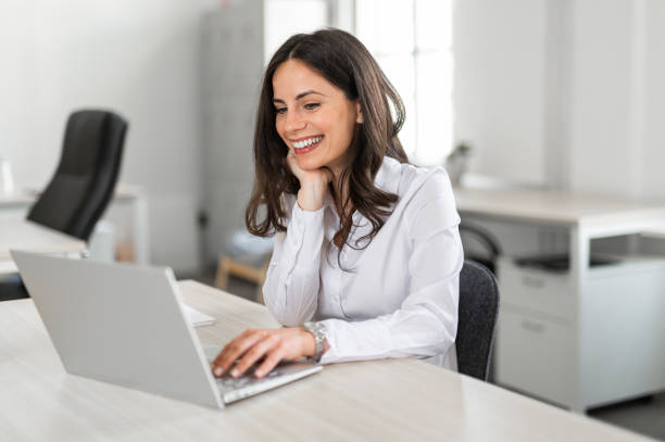 istock Young businesswoman smilling while working on her computer at her desk in bright modern coworking office 2161449449