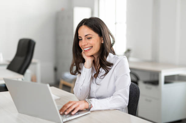 istock Young businesswoman smilling while working on her computer at her desk in bright modern coworking office 2161449519