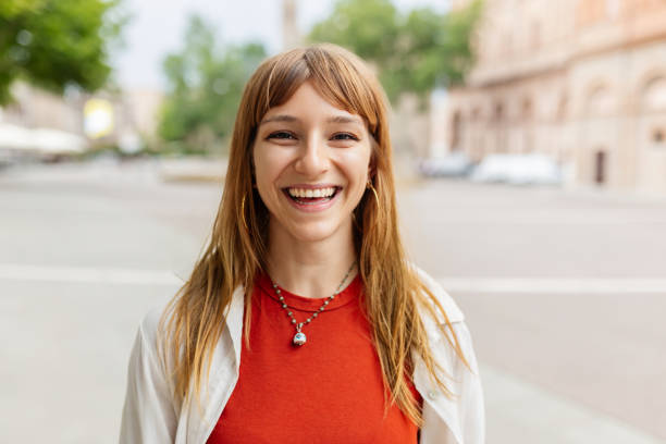 Happy young caucasian girl smiling at camera standing at city street. stock photo