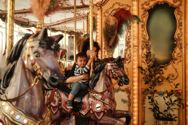 istock Little boy holding pole while riding carousel horse with mother 2161453409