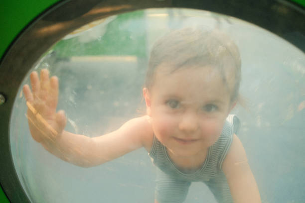 Happy toddler boy explores a playground, touching a glass dome with wonder and joy, capturing the essence of childhood adventure