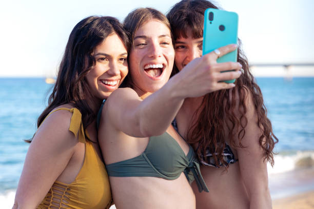 istock Three young friends in summer dresses taking selfie on the beach. 2161453989