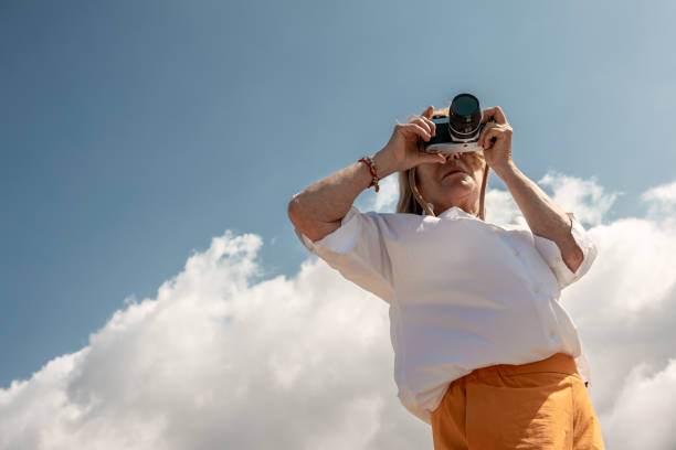 istock Senior Woman taking photos with a vintage camera outdoors, copy space. 2161454884