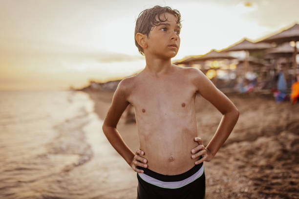 istock Young boy standing confidently by the beach at sunset 2161458840