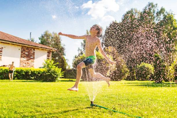 istock Brothers jumping over sprinklers 2161460453