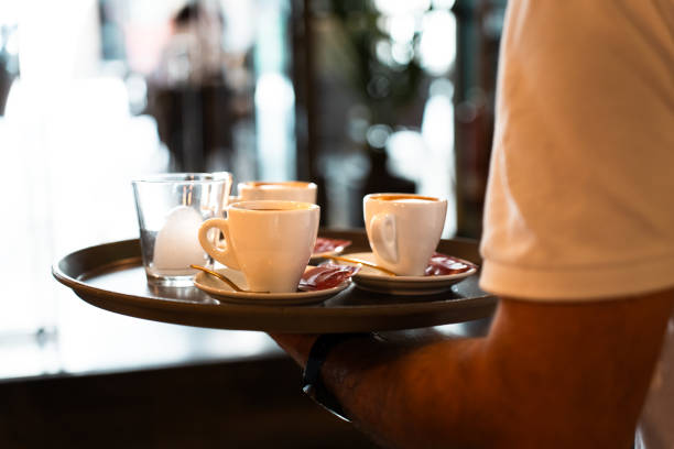 Close-up of a tray with coffees held by a waiter.