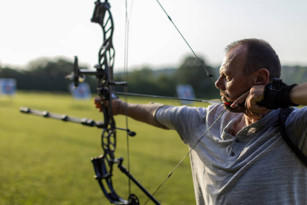 istock Man with prosthetic arm practicing archery with compound bow on the training field 2161461160