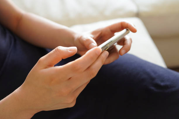 Young woman watching a video on the sofa with her smartphone held horizontally