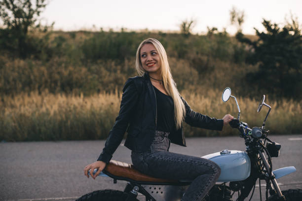 istock Pretty blonde girl in a leather jacket on a motorcycle at sunset. 2161468430