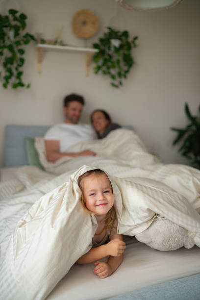 istock Cute girl lying in bed whit her parents 2161468907