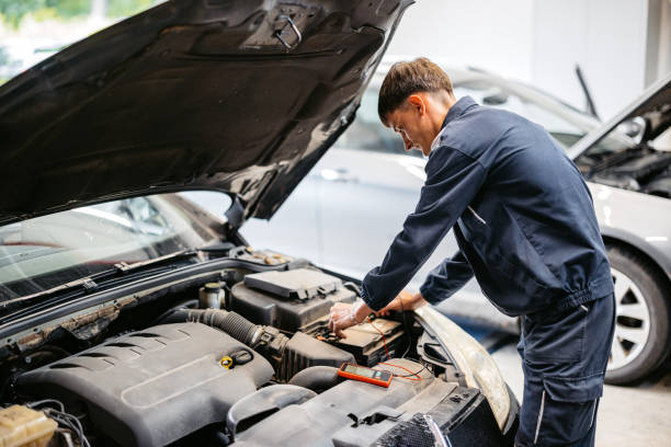 istock Young Car Mechanic Checking Voltage On A Car Battery In His Garage 2161472235