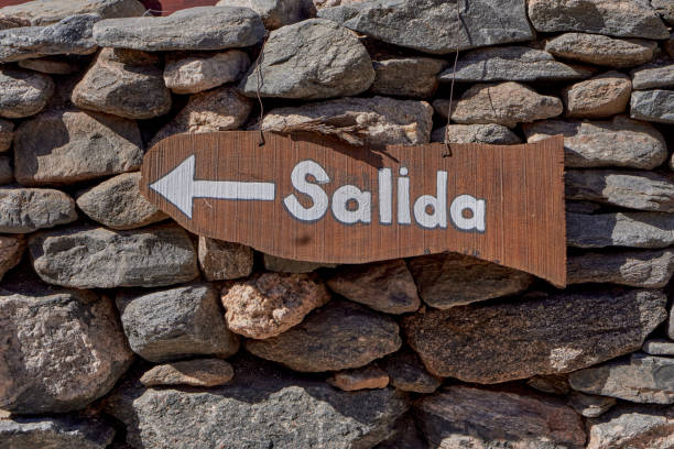 Wooden exit sign with a directional arrow on a rustic stone wall.