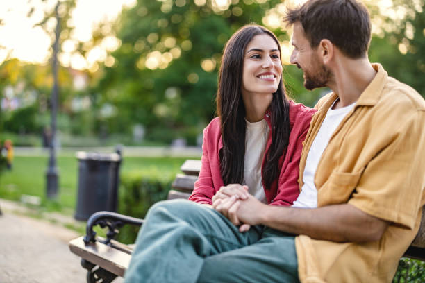 istock Couple holding hands on a park bench smiling 2161478354