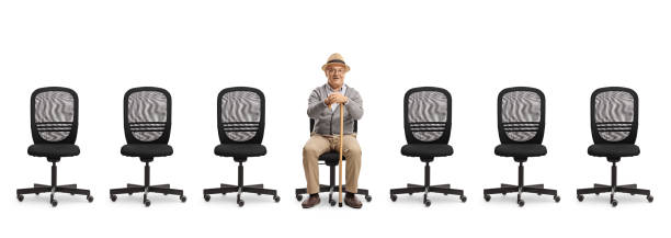 istock Elderly man sitting on a desk chair with empty chairs in a line 2161480534