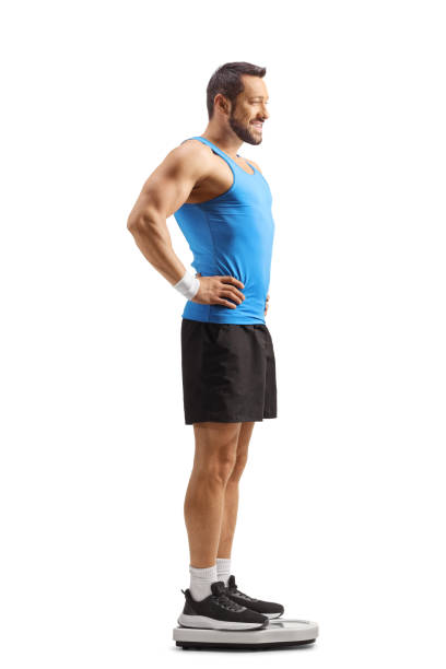 Fit man in sportswear checking weight on a scale isolated on white background