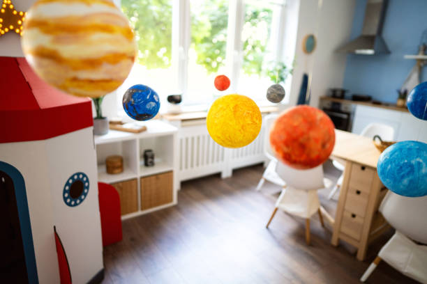 istock Cardboard rocket ship and wall hanging solar system at the modern apartment 2161481437
