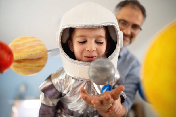 istock Boy in a space suit playing with his dad at home, imagining space travel. 2161481444