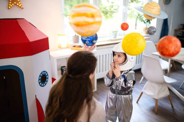 istock Boy in a space suit playing with his mom at home, imagining space travel. 2161482304