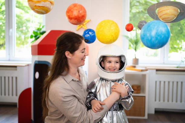 istock Boy in a space suit playing with his mom at home, imagining space travel. 2161482486