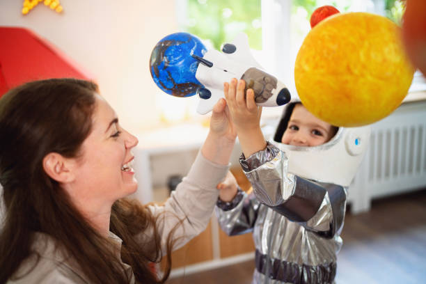 istock Boy in a space suit playing with his mom at home, imagining space travel. 2161483878