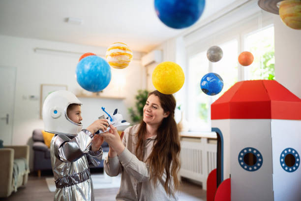 istock Boy in a space suit playing with his mom at home, imagining space travel. 2161483965