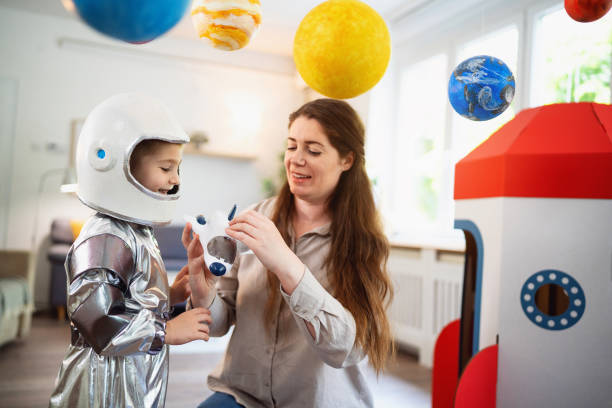 istock Boy in a space suit playing with his mom at home, imagining space travel. 2161484021