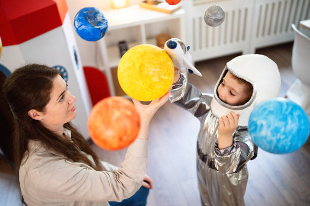 istock Boy in a space suit playing with his mom at home, imagining space travel. 2161484258