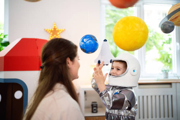 istock Boy in a space suit playing with his mom at home, imagining space travel. 2161484324