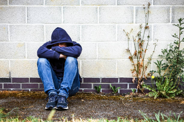 istock Depressed homeless man sitting outside abandoned building 2161485825