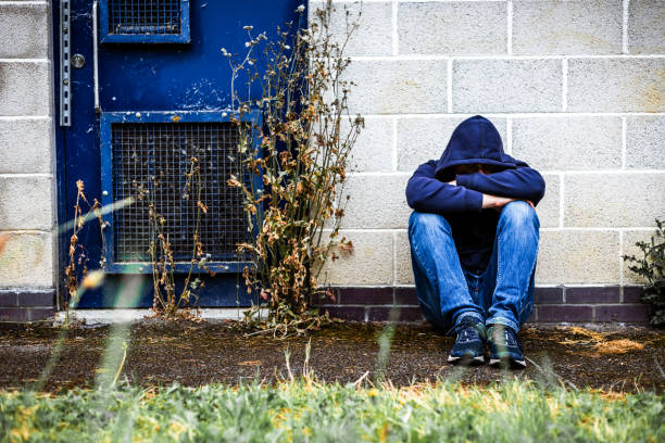 istock Depressed homeless man sitting outside abandoned building 2161485997