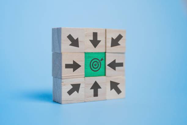 istock A stack of wooden blocks with various arrows pointing towards a target center on a blue background. 2161487040